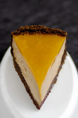 Selective focus to slice of brownie cheesecake covered with mango jelly.