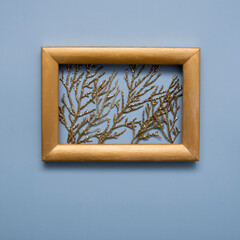 Golden twigs in glitter in a gold frame on a blue background. New year christmas concept
