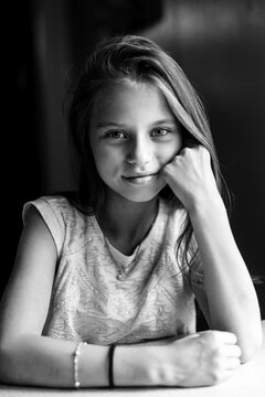 Teen girl posing for the camera sitting at the table. Black and white photography.