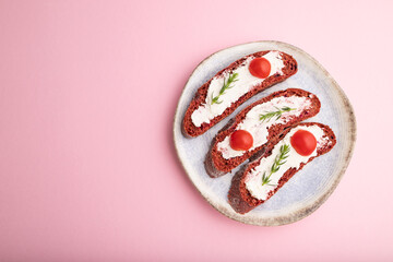 Red beet bread sandwiches with cream cheese and tomatoes on pastel pink background. top view, copy...