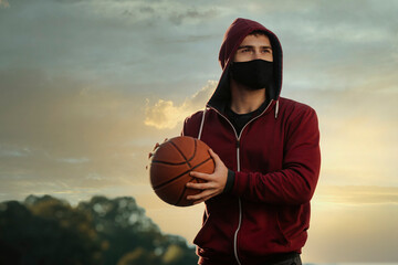 A young man with a face mask holding a basketball.