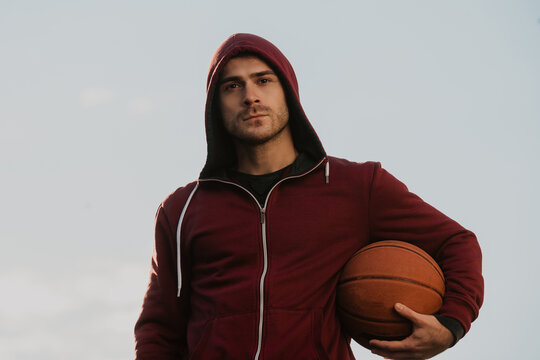 A Young Man With A Face Mask Holding A Basketball.