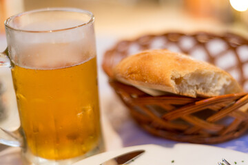 Cold draft lager beer in a glass mug,next to some partially eaten freshly made bread in a basket,Podgorica,Montenegro.