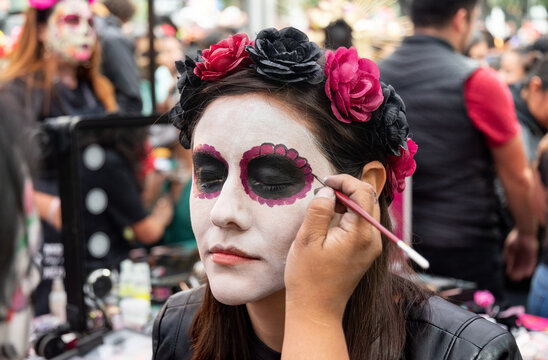 Woman in process to be converted into a catrina with a rose tiara in the traditional day of the dead in Mexico city