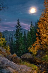 Mountain peak in Rocky Mountain National Park near Estes Park in Colorado. Taken in the evening of the night sky, fall leaves, stars, and moon.