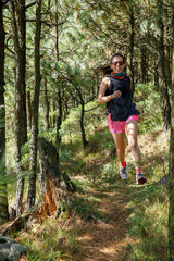 Atleta corriendo en un sendero de la montaña rodeada de arboles