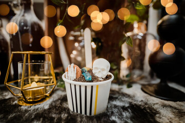 cupcake ice cream with scary skeleton and worm graveyard on a dark golden bokeh background.sweets for the celebration of Halloween.Halloween party food celebration in holidays.Delicious dessert party.