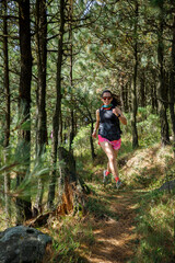Atleta corriendo en un sendero de la montaña rodeada de arboles