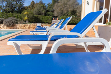 blue cushion deckchair on the edge of a swimming pool in summer