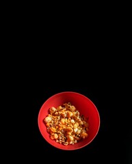 Popcorn bowl with cheese on black background, cinema concept