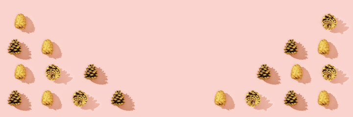 Christmas decorations from natural pine cone painted golden colored on pink.