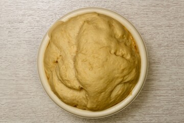 The airy yeast dough came up in a light large round bowl. The process of fermentation of yeast in the flour mixture.