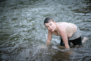Boy swimming in river looking off into the distance