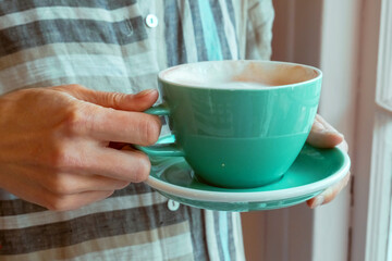 Cup of morning coffee in the hands of a young woman.