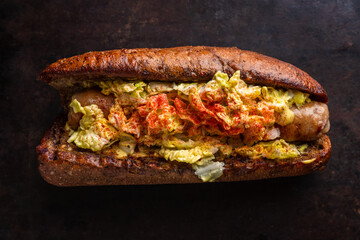 Healthy and tasty hot-dog with big grilled sausage, fresh green cabbage and sauce. Selective focus. Shallow depth of field.