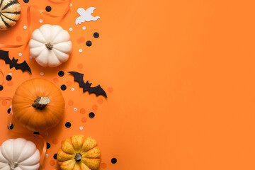 Halloween decorations: bats, pumpkins and ghost on orange background. Flat lay composition, top view with copy space.