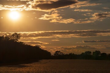 This scenic image shows a glowing evening sky cloudscape over a serene, remote field landscape.