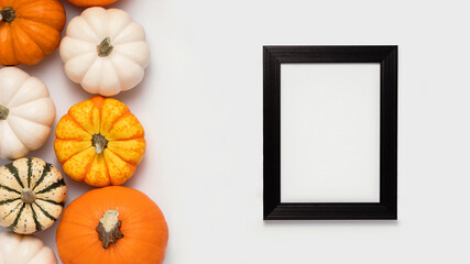 Black frame and pumpkins on white background with place for text. Halloween flat lay composition, top view.