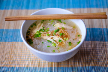 Chicken noodles with clear soup and wood chopsticks on the table