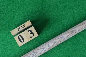 July 3, Number cube with a snooker stick on a green background, snooker table.