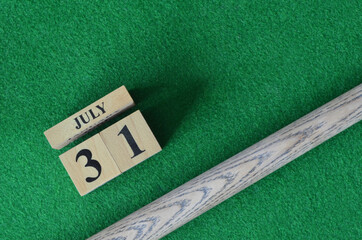 July 31, Number cube with a snooker stick on a green background, snooker table.