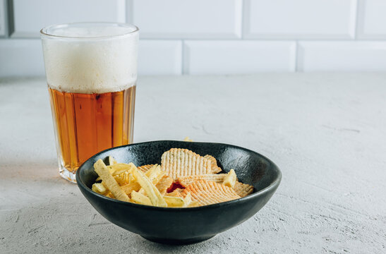 Beer Glass And Potato Chips In A Black Bowl On Concrete Background - Snack Bar Or Pub Menu