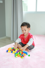 Portrait of asian little baby boy playing colorful plastic blocks and lying on bed