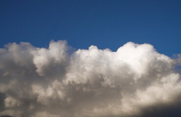 This image shows huge puffy white clouds in bright blue sky. 