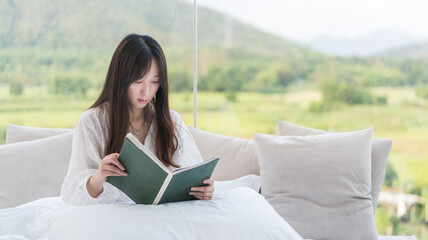 Young girls with long hair sitting on the bed reading a book