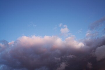 This dreamlike image features fluffy white clouds moving across a beautiful summer blue sky.