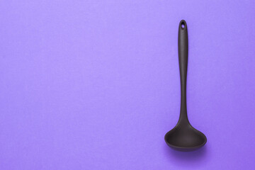 Brown silicone ladle on a lilac background.