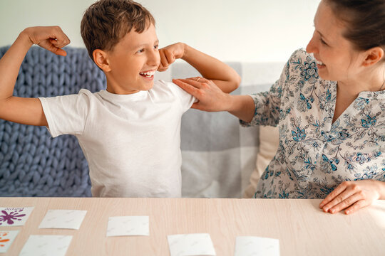 Mom and son play flashcards. boy wins and shows strength, muscles in his arms.