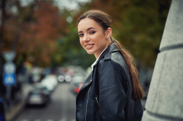 Young beautiful girl in a fashionable leather jacket on a city street