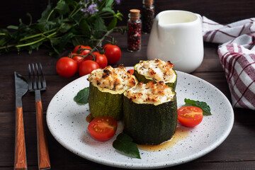 Baked stuffed zucchini columns with minced chicken and vegetables on a plate. Dark wooden background. Copy space.