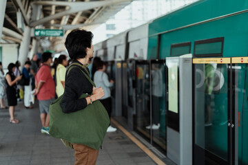 Asian man waiting for a train on platform.