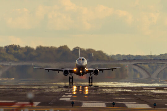  An Airplane is taking off from the runway of DCA airport at sunset. The exhaust and evaporation of jet fuel creates massive blurring and air pollution.