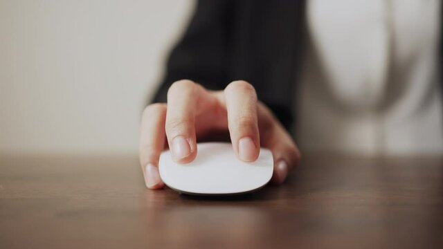 Hand using white mouse button on the office desk.