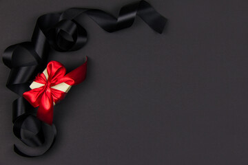 gift for black Friday and Christmas. Box with a red ribbon on a black background