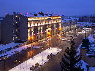 Naklejka premium The Hermitage-Siberia Museum of Fine Arts in Omsk at Museum . The square and park near a beautiful historic building with illumination in the evening in winter.