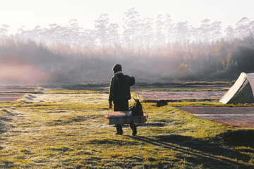 An old man walked with his wares walking in the morning, in the middle of a misty meadow
