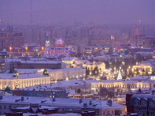 The historical center of Omsk from a height: Lenin Street, the Drama Theater and the Assumption Cathedral in the evening in the winter with the lights on.