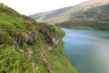 A high cliff on the shores of a picturesque turquoise lake.