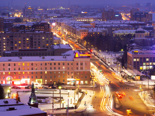Fototapeta na wymiar Marx Street that goes into the distance on a winter evening in Omsk, a theater square near the Omsk Musical Theater