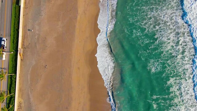 Aerial view above waves and a empty Municipal Beach, during sunrise, in Palm Beach, Miami, Florida, USA - top down, drone shot