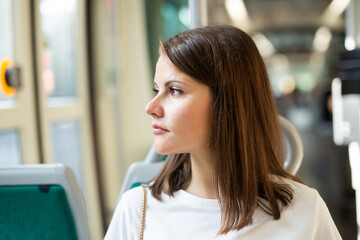 Portrait of positive girl passenger enjoying trip at public transport in modern tram