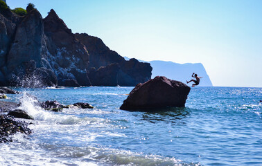 Crimean coast. A child jumps off a cliff into the water. Sevastopol.