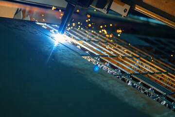 CNC cutting machine cuts a sheet of metal. Many sparks and incandescent drops of metal.