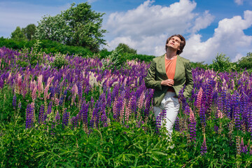 Tall handsome man standing on lupine flowers field