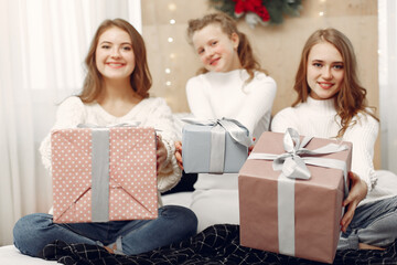 Fototapeta na wymiar Girls sitting on the bed. Women with gift boxes. Friends preparing for Christmas.