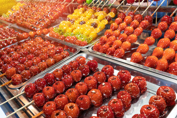 Tanghulu traditional Chinese dessert candied fruit on a wooden stick. Sugar candy Chinese dessert...
